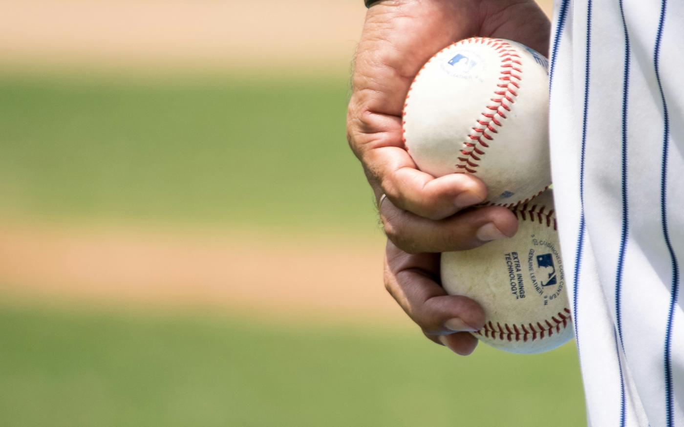 man holding two white baseballs by Jose Francisco Morales courtesy of Unsplash.