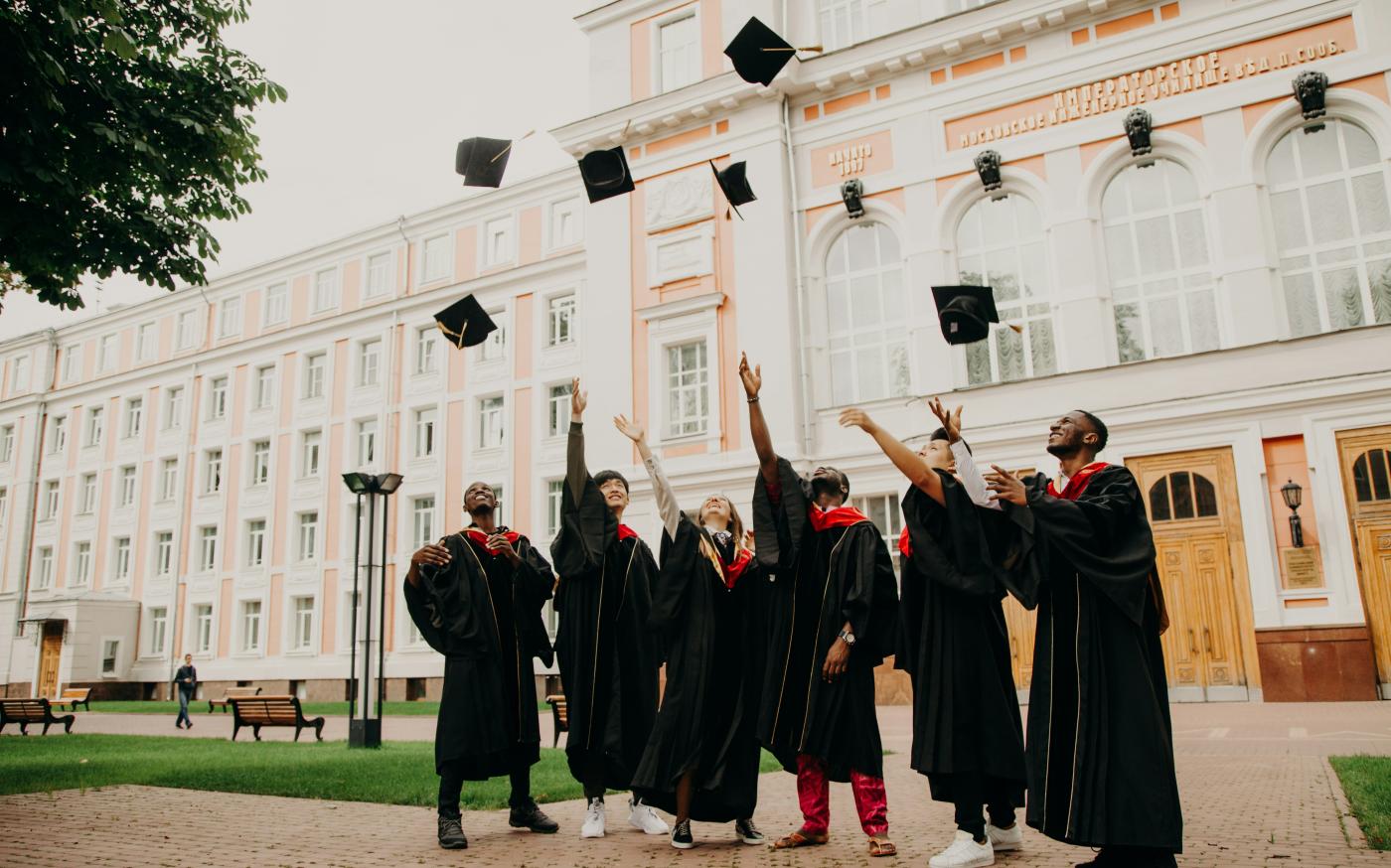 people in black academic dress standing on green grass field during daytime by RUT MIIT courtesy of Unsplash.