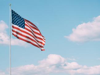 flag of U.S.A. under white clouds during daytime by Aaron Burden courtesy of Unsplash.
