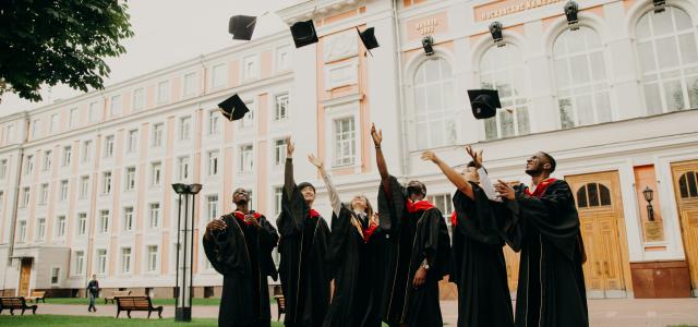 people in black academic dress standing on green grass field during daytime by RUT MIIT courtesy of Unsplash.